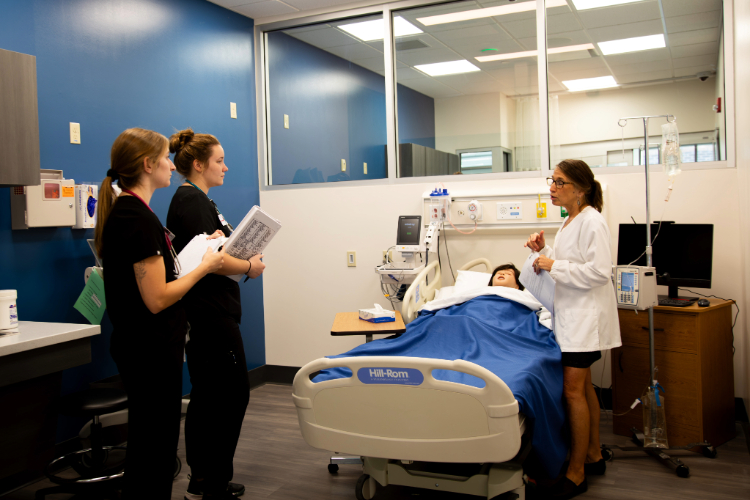 Lakeshore students listen to an instructor sharing how the patient simulator helps them with their learning experience.
