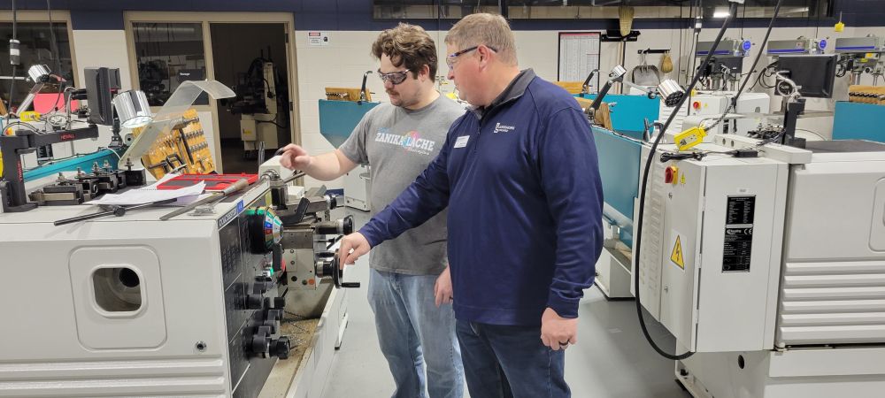 Mark Lorier provides guidance to Ted Simmons, a CNC Automation Technician student.