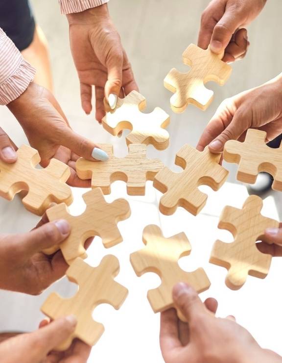 Multiple hands holding puzzle pieces