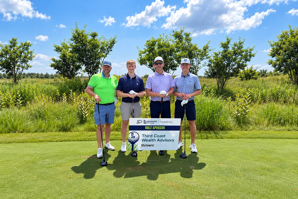 Participants of LTC Foundation Golf Event standing on a golf green by a lake